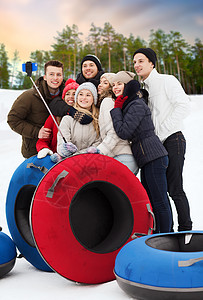 休闲,技术人的群微笑的十几岁的朋友用雪管拍照智能手机自拍棒冬天的自然背景下户外冬天雪管自拍的朋友图片