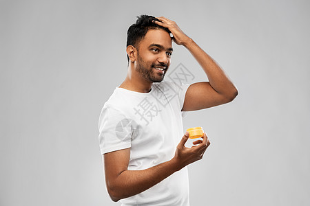 修饰,发型人的微笑的轻印度男子应用头发蜡造型凝胶灰色背景印度男人涂发蜡定型凝胶图片