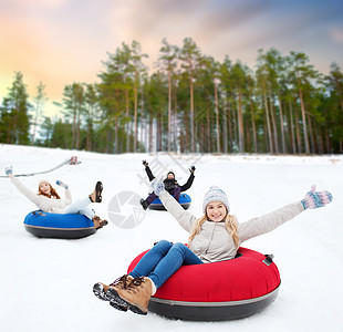 冬季,休闲娱乐活动的群快乐的朋友自然背景下的雪管上滑山快乐的朋友雪管上滑下山背景图片