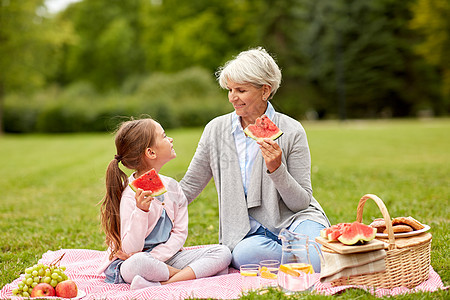 家庭休闲人的快乐的祖母孙女夏季公园野餐时吃西瓜祖母孙女公园野餐图片