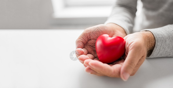 爱,健康,心脏病学慈善杯老人的手与红色的心形用红色心形的高级男人的手图片