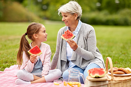 家庭休闲人的快乐的祖母孙女夏季公园野餐时吃西瓜祖母孙女公园野餐图片