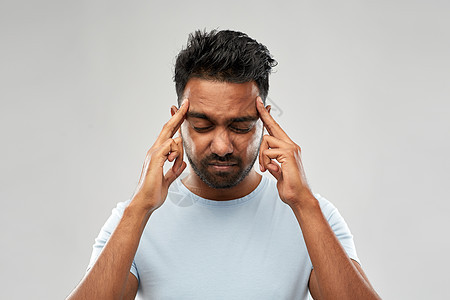 人,健康问题压力幸的印度男人灰色背景下头痛幸的印度男人头痛图片