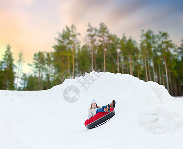 冬天,休闲娱乐活动的快乐的十几岁女孩滑下雪管下山快乐的少女雪管上滑下山背景图片