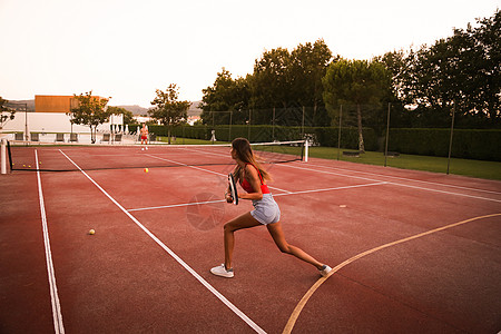 夫妇球场上打网球自然的日落光图片