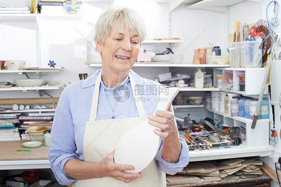 陶器工作室里着花瓶的高级女人图片