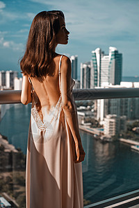 轻的美女阳台上俯瞰着摩天大楼的城市景观美好的早晨时尚美丽图片