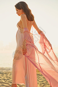 穿着粉红色连衣裙的美丽孕妇的户外大气生活方式肖像美好的早晨海滩上的日出美丽时尚图片