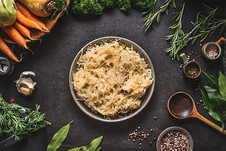 酸菜碗黑暗的乡村厨房桌子背景与烹饪勺子配料,顶部视图健康清洁素食低热量食品图片