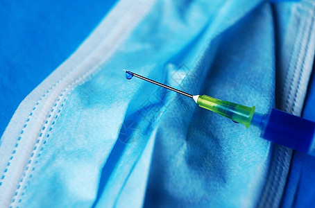 种带蓝色液体的注射器的详细,带蓝色背景的医用罩上的针头背景图片