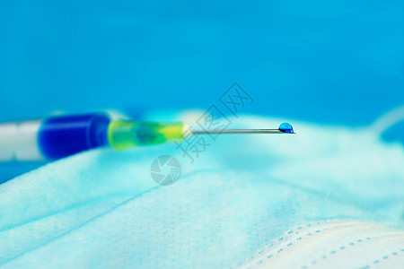 种带蓝色液体的注射器的详细,带蓝色背景的医用罩上的针头图片