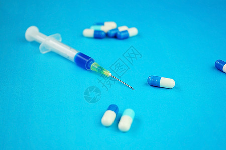 带针头蓝色背景的药丸的注射器的详细背景图片