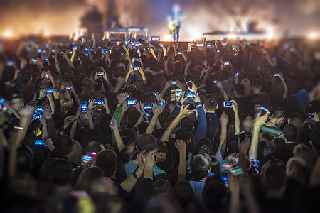 人们音乐会上用手机拍摄节目图片
