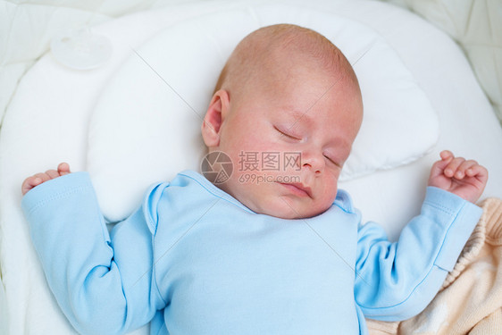 三个月的婴儿穿着蓝色的衣服睡篮里图片