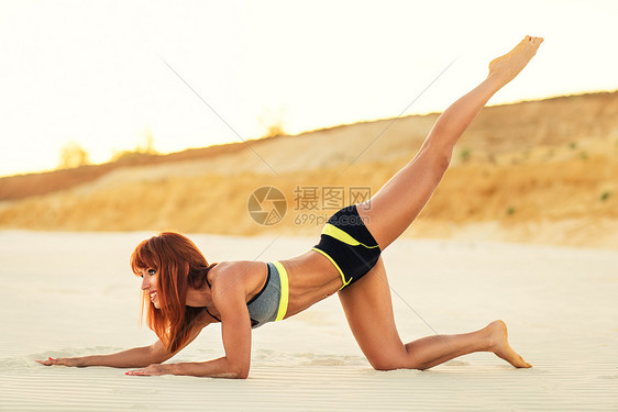轻的苗条感运动女人沙滩上户外伸展图片