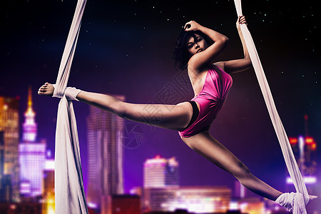 轻女子体操运动员夜间现代城市背景图片