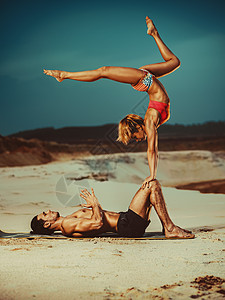 轻的体育夫妇沙滩上阿克罗伊加练图片