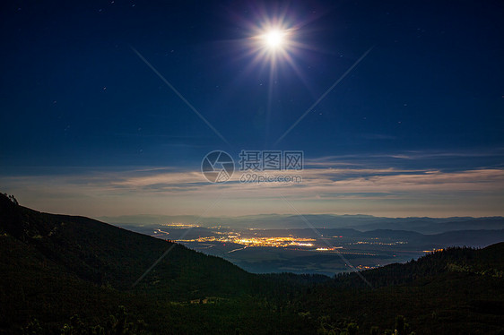 山上灯光城镇的明月夜景图片