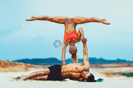 轻的体育夫妇沙滩上阿克罗伊加练图片