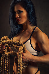 感强壮的黑发健身女子与大绳身体上的纹身穿孔图片