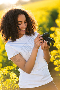 美丽的快乐混合种族非裔美国女孩十几岁的女轻女子阳光下微笑,用相机拍照图片
