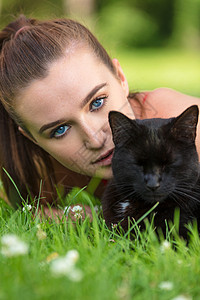 美丽的少女少女,蓝眼睛的轻女人,只黑猫躺草地上图片