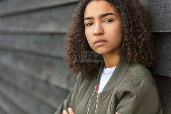 美丽的混血非裔美国女孩十几岁的女轻女子穿着绿色轰炸机夹克,看上悲伤沮丧体贴图片