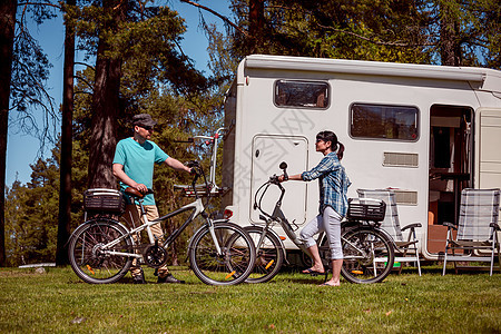 女人个骑电动自行车的男人营地休息女人个骑电动自行车的男人营地休息家庭度假旅行,假日旅行汽车房车,商队汽车度假图片