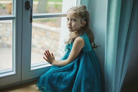 悲伤的女孩透过窗户看着图片