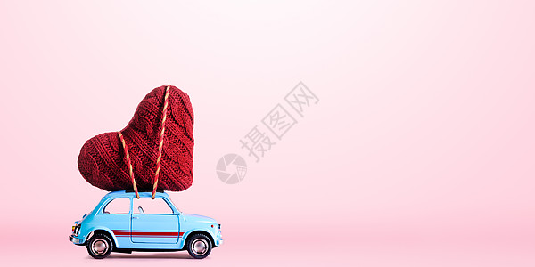 蓝色复古玩具汽车为情人节提供粉红色背景的工艺心图片