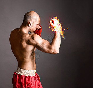 打拳击手武术战士灰色背景上用火热的手击球图片