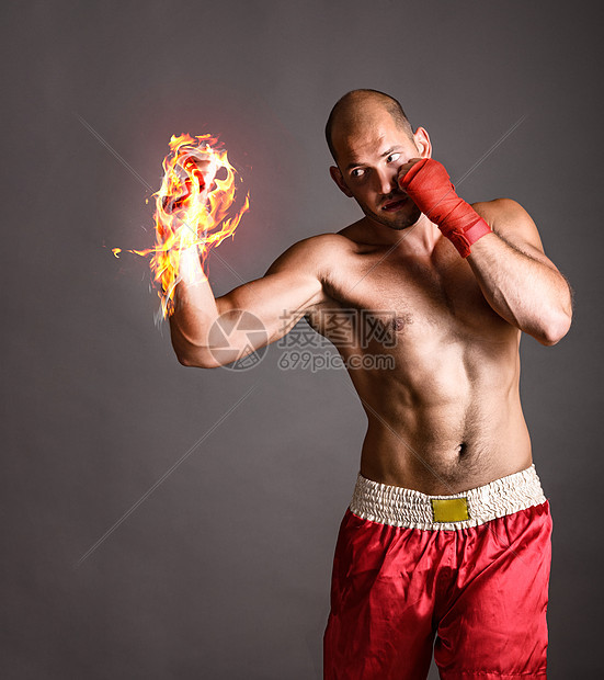 打拳击手武术战士灰色背景上用火热的手击球图片