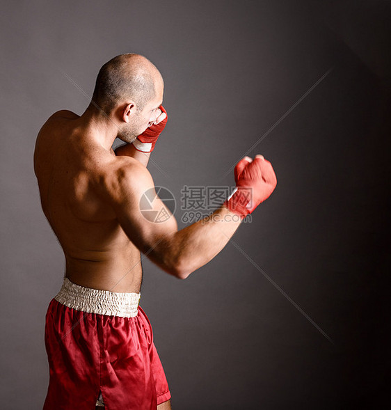 强壮的拳击手武术战士灰色背景上用火热的手击球图片