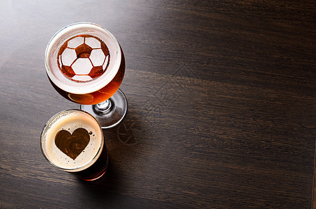 喜欢足球啤酒心足球的轮廓两杯新鲜啤酒酒吧的桌子上,看图片