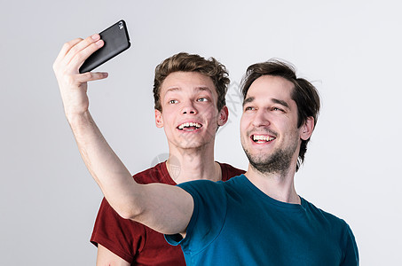 快乐的朋友正自拍两个快乐的朋友手机摄像头上自拍图片