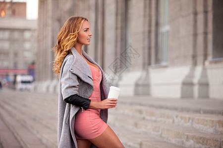 个漂亮的女人着咖啡抗城市场景图片