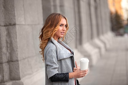 个漂亮的女人着咖啡抗城市场景图片