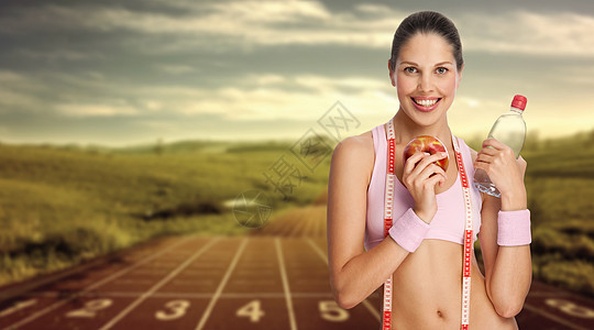 位轻的运动女子着水苹果抗跑道图片