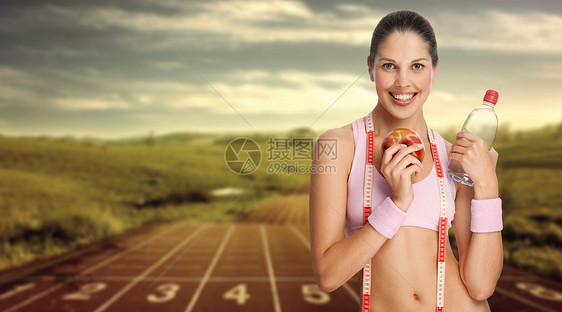 位轻的运动女子着水苹果抗跑道图片