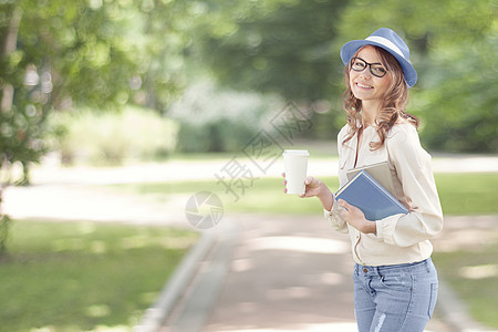 快乐的轻学生喝着咖啡,走夏天的公园里,着书读书学图片