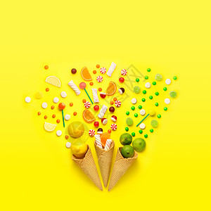 创造的静物照片三个华夫饼锥与糖果,水果棉花糖黄色背景图片
