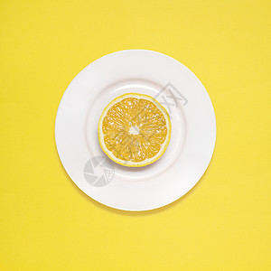 黄色背景的白色盘子上的柠檬片图片