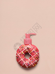 创意静物的美味甜草莓甜甜圈与化妆品泵分配器粉红色的背景图片