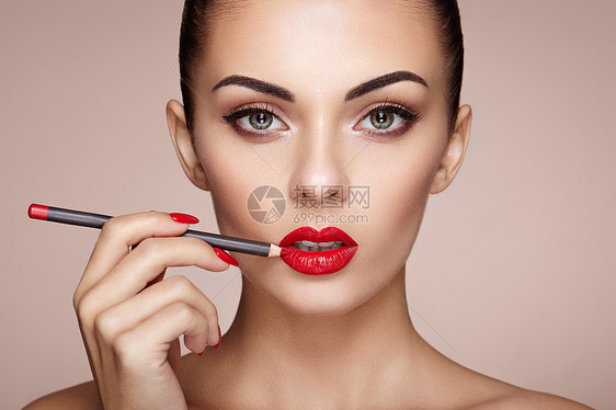 美丽的女人用口红涂嘴唇漂亮的女人脸化妆细节美丽的女孩完美的皮肤红唇指甲修剪图片