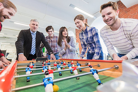 人们踢桌子足球员工休息时间办公室玩桌球室内游戏图片