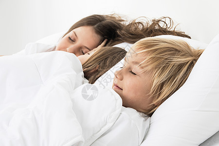 三个孩子睡床上三个漂亮的孩子睡条白色毯子下的床上图片
