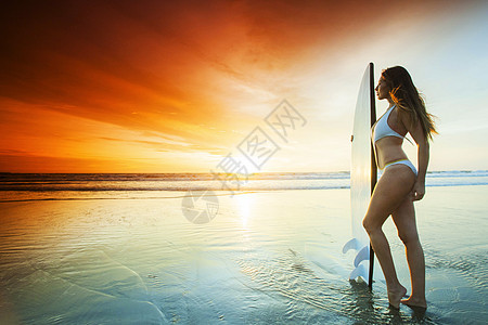 海滩上的冲浪女孩日落时海滩上美丽感的冲浪女孩图片