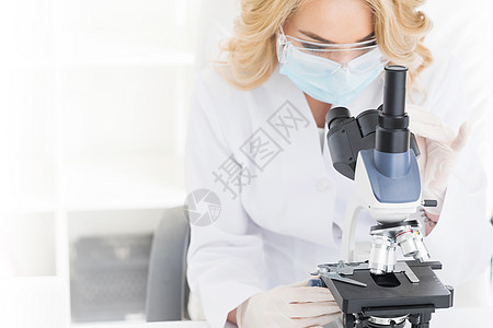 女医生透过显微镜看女医生显微镜观察,工作室白色背景上拍摄图片