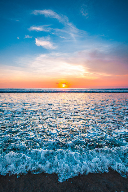 日落海洋上美丽的日落天空背景前溅海浪图片