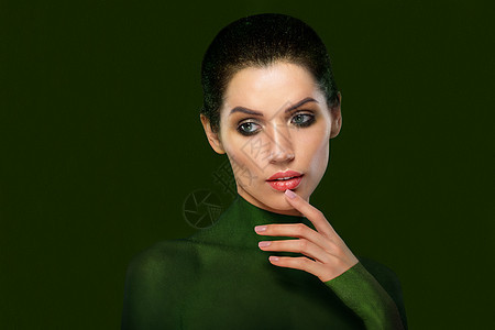 绿色背景上美丽女人的肖像特写脸想想吧拇指靠近嘴唇图片